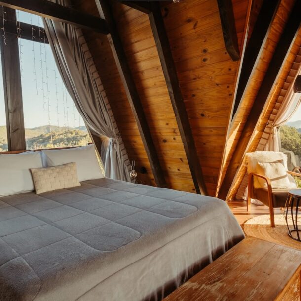 A cozy resort room with a large bed, fireplace, and scenic window view, suggesting a comfortable stay at budget-friendly resorts in Pakistan.