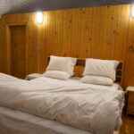 A comfortable bed inside a luxury dome accommodation in Pakistan, featuring wooden walls and warm lighting.