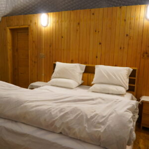 A comfortable bed inside a luxury dome accommodation in Pakistan, featuring wooden walls and warm lighting.