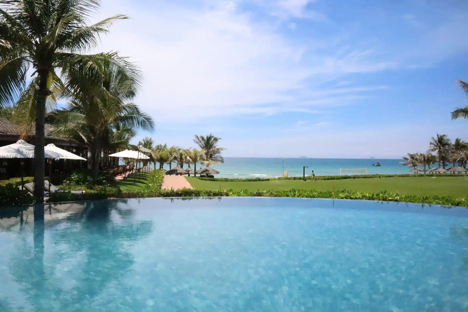 An infinity pool overlooking a tropical beach with palm trees and the ocean, representing a wide range of resort activities available.