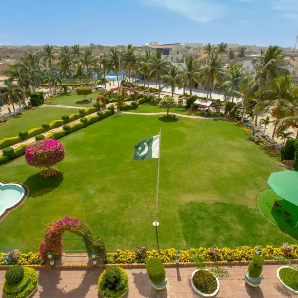 A lush green lawn with a Pakistani flag, surrounded by resort buildings, representing a spacious and professional venue at one of the Best Resorts for Team Building in Pakistan.